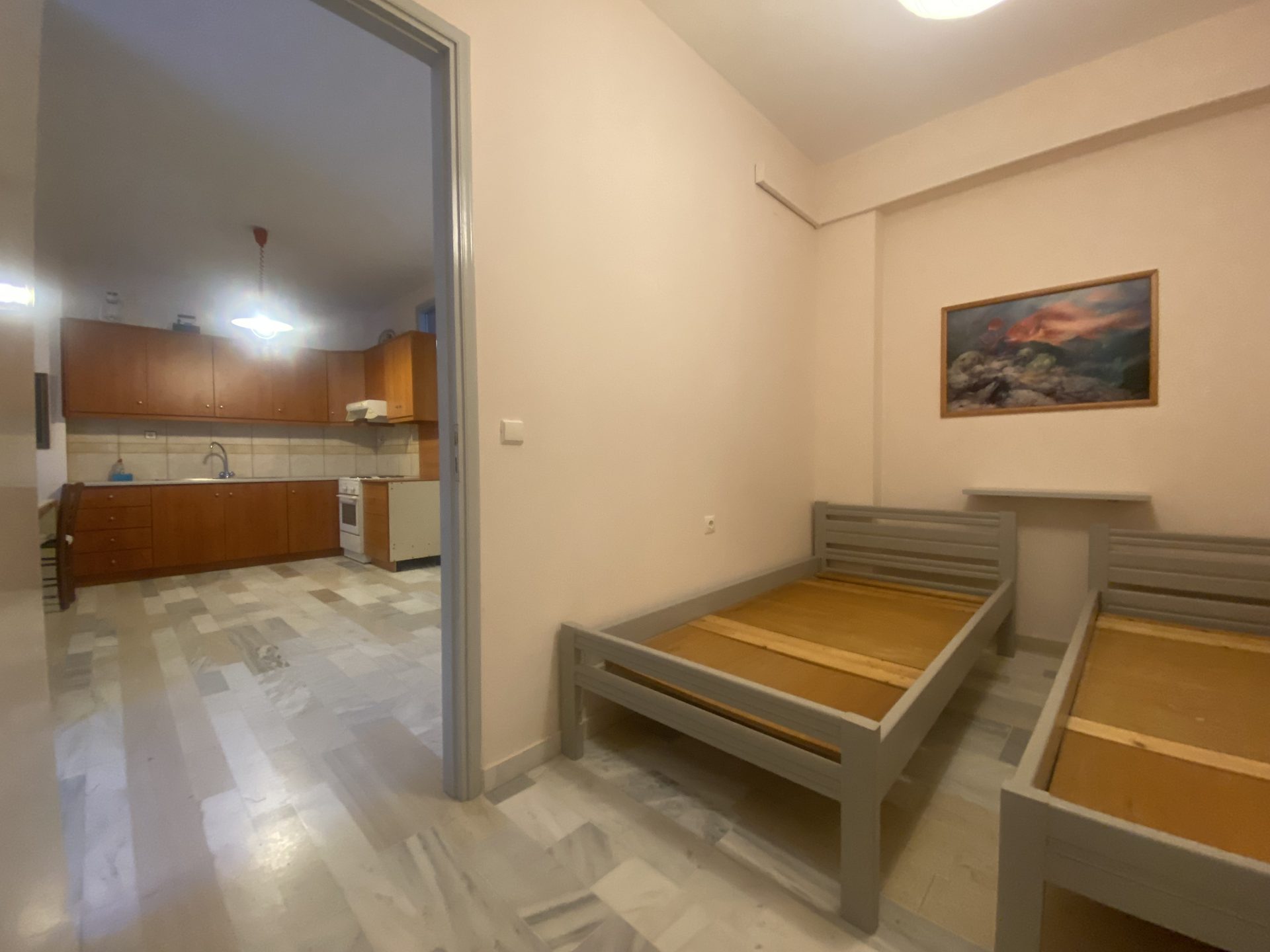 Garden-level bedroom with twin beds and access to kitchen