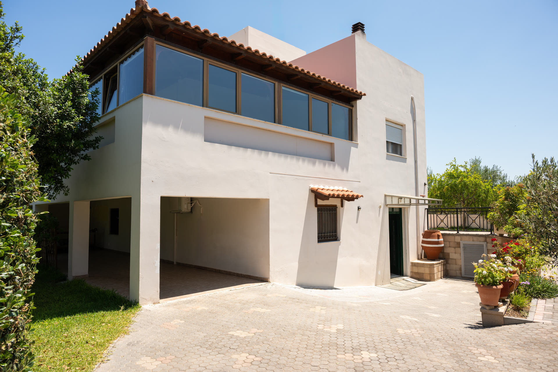 Clean side facade of the house with driveway, garden planting, and upper sunroom windows