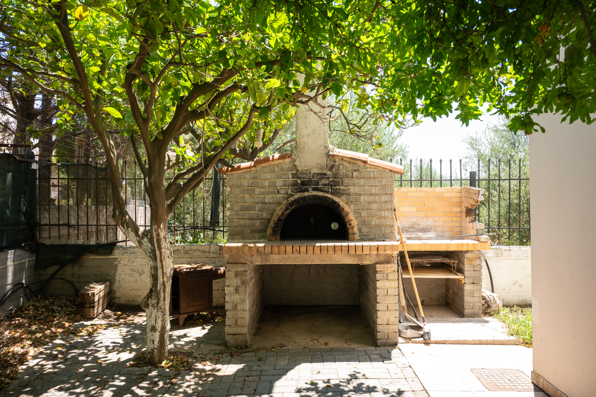 Traditional outdoor wood-fired oven beneath mature garden trees