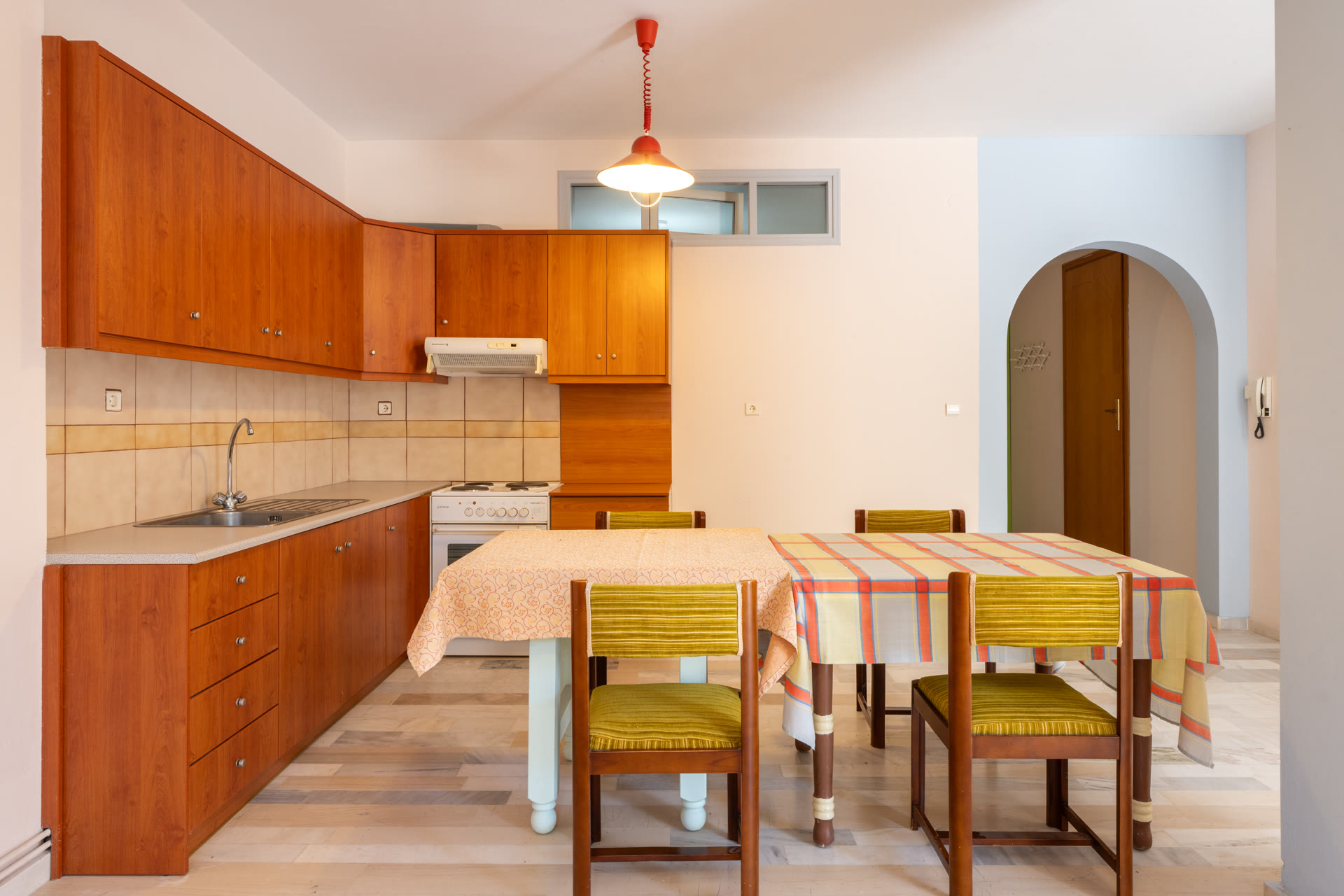 Garden-level apartment kitchen with wood cabinets, dining table, and arched doorway