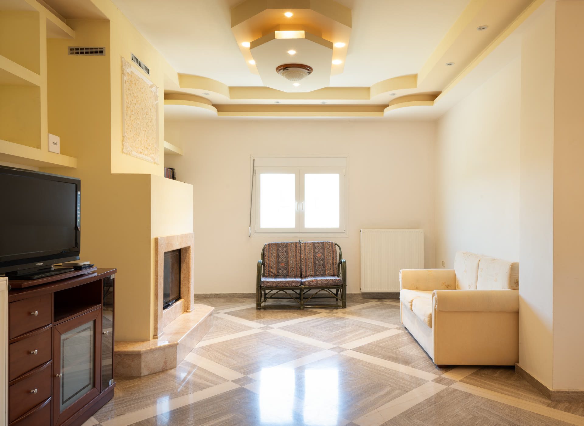 Bright sitting area with fireplace, sofa, decorative ceiling, and polished floor