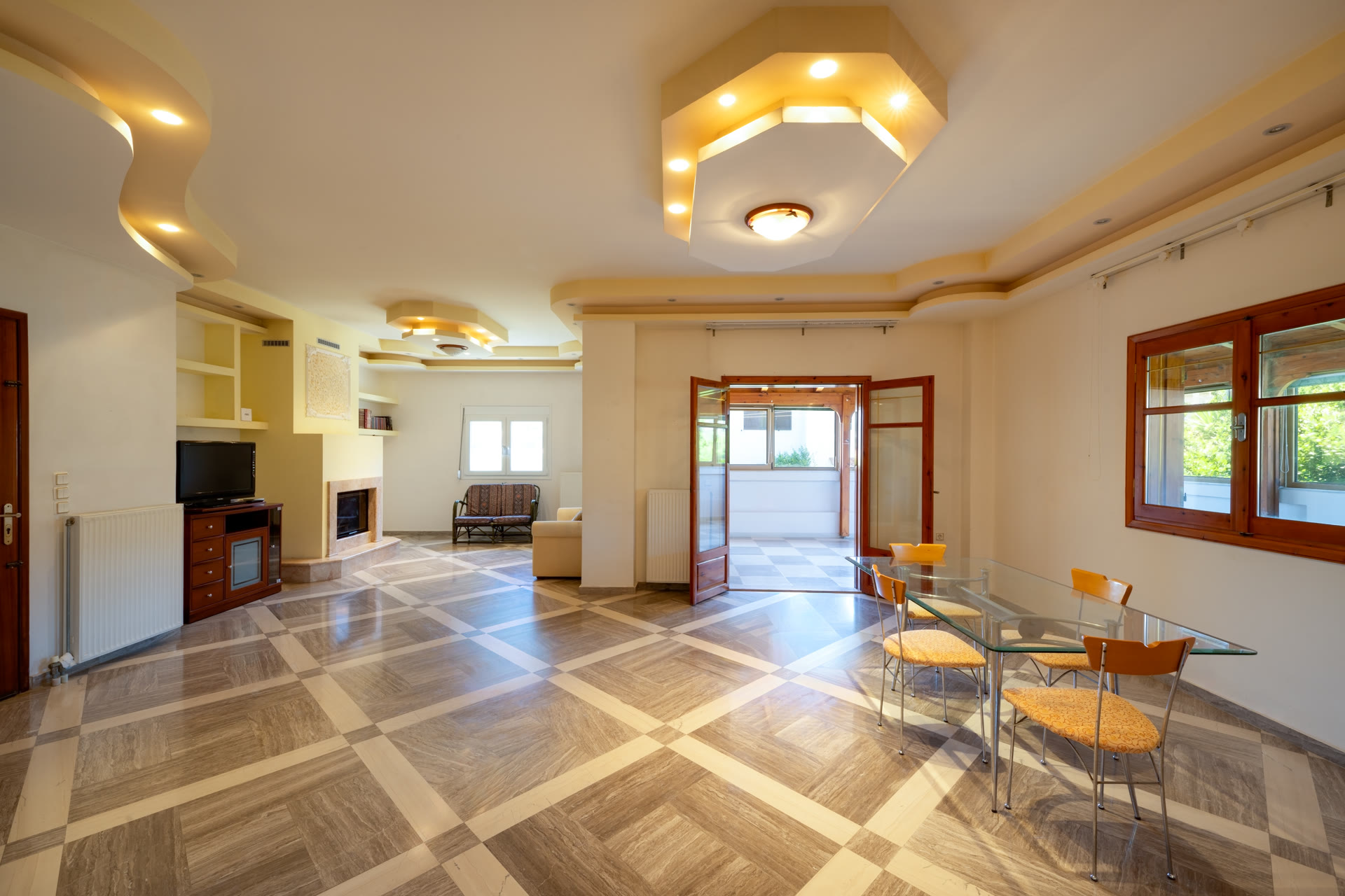 Spacious main living and dining area with fireplace, marble-pattern floors, and access to the enclosed terrace