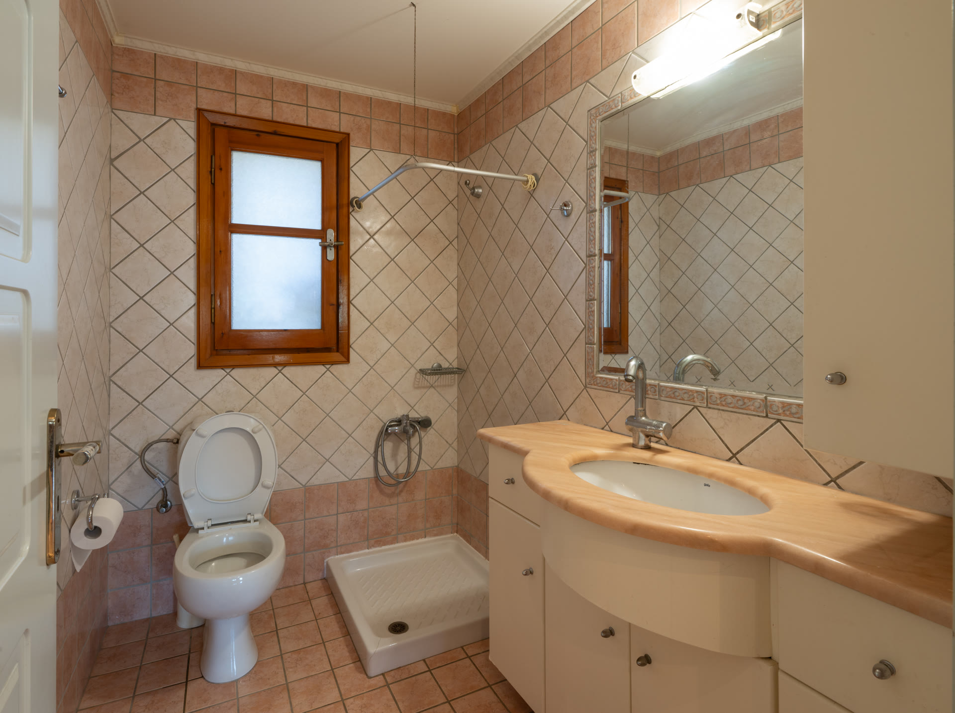 Second bathroom with shower area, toilet, vanity, mirror, and wood-framed window