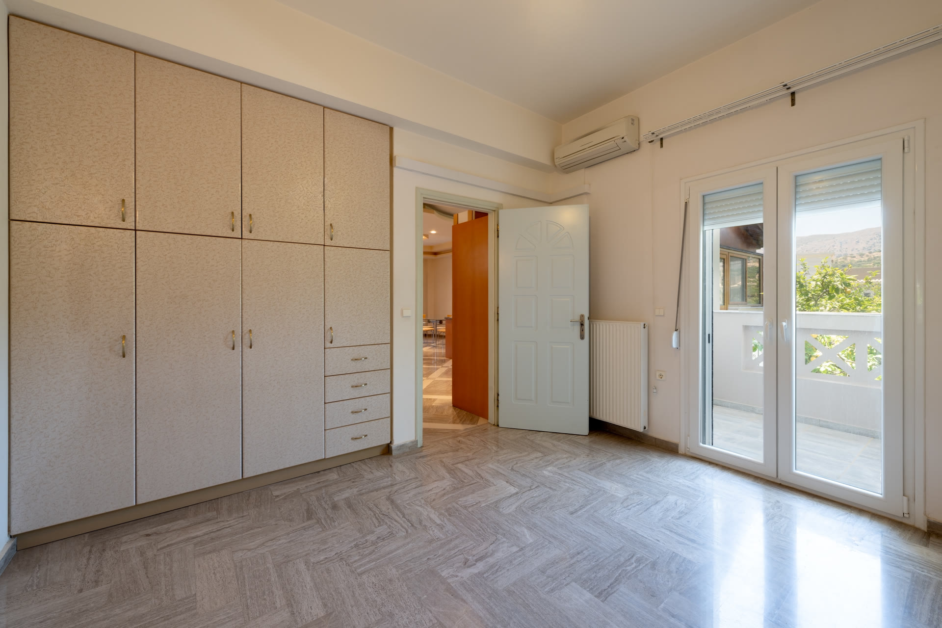 Bedroom with built-in wardrobes, air conditioning, and balcony doors with countryside view