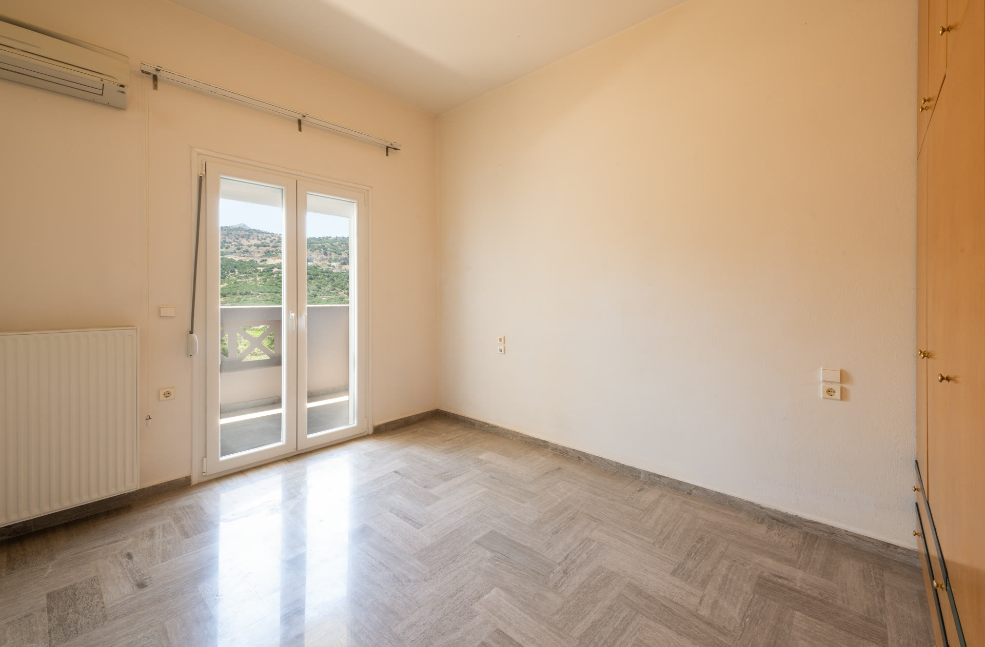 Bright bedroom with window view, air conditioning, and polished floor