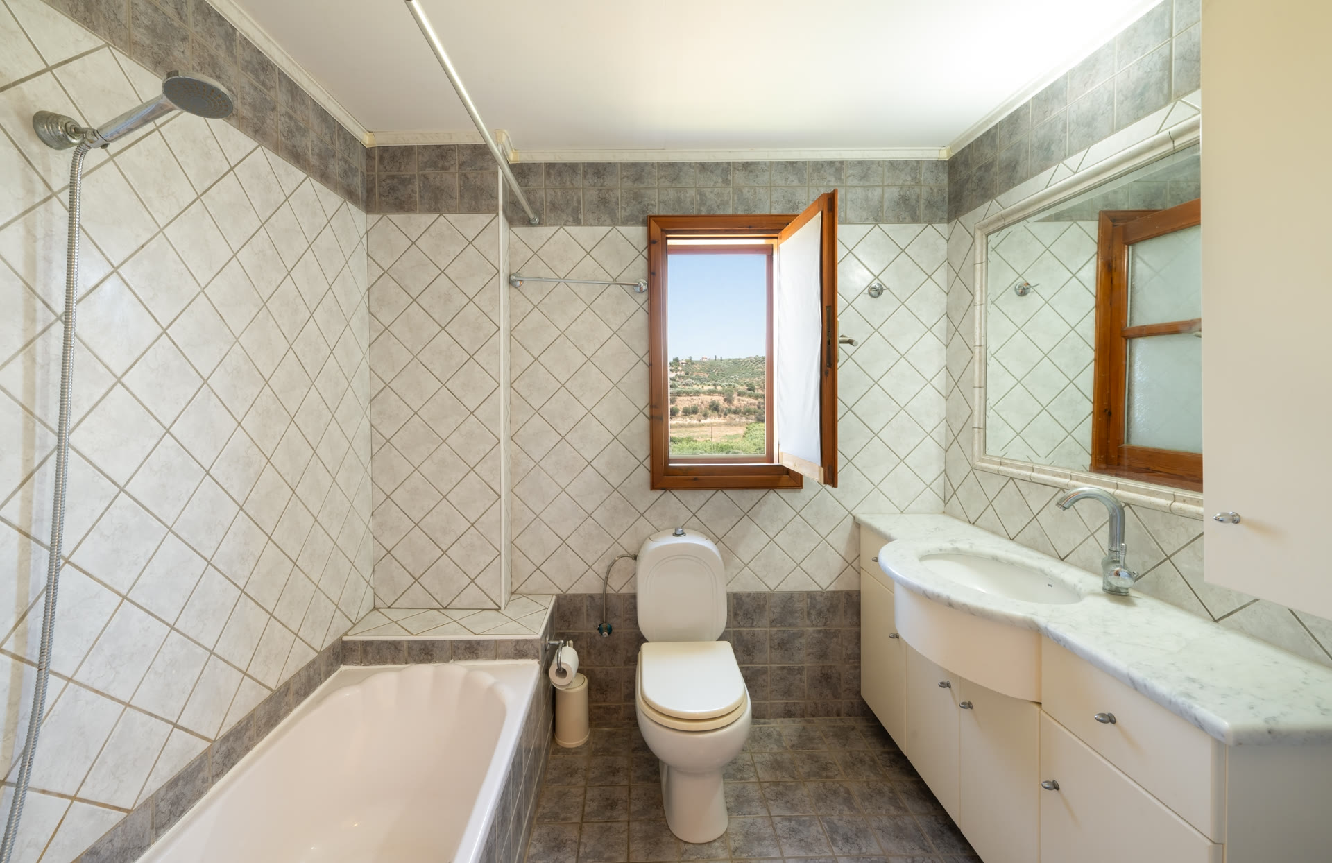 Main bathroom with bathtub, wide vanity, mirror, and window view