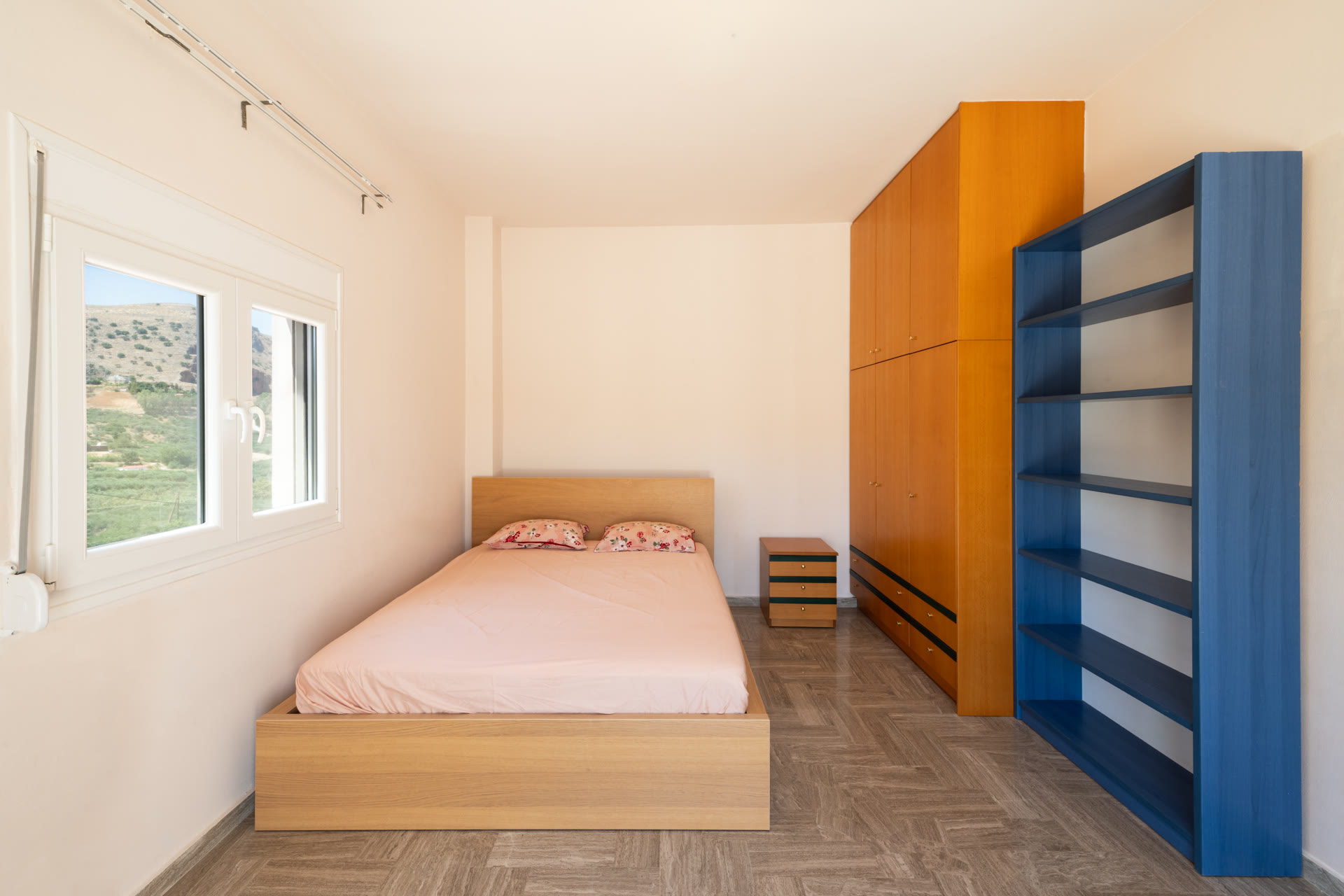 Bedroom or home office with bed, shelving, wardrobe, and countryside-facing window