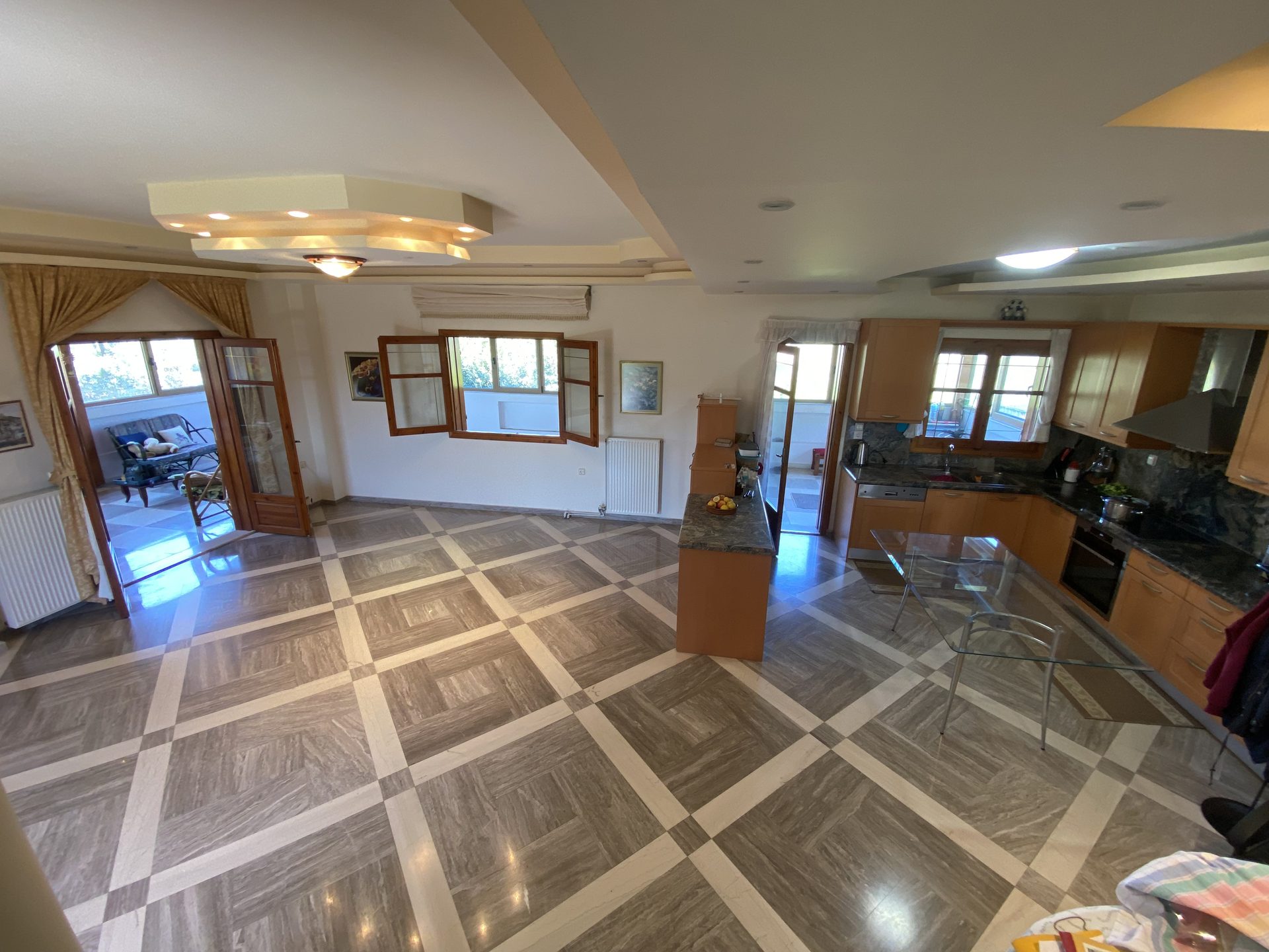 Open-plan living and kitchen area with marble floors and garden-facing windows
