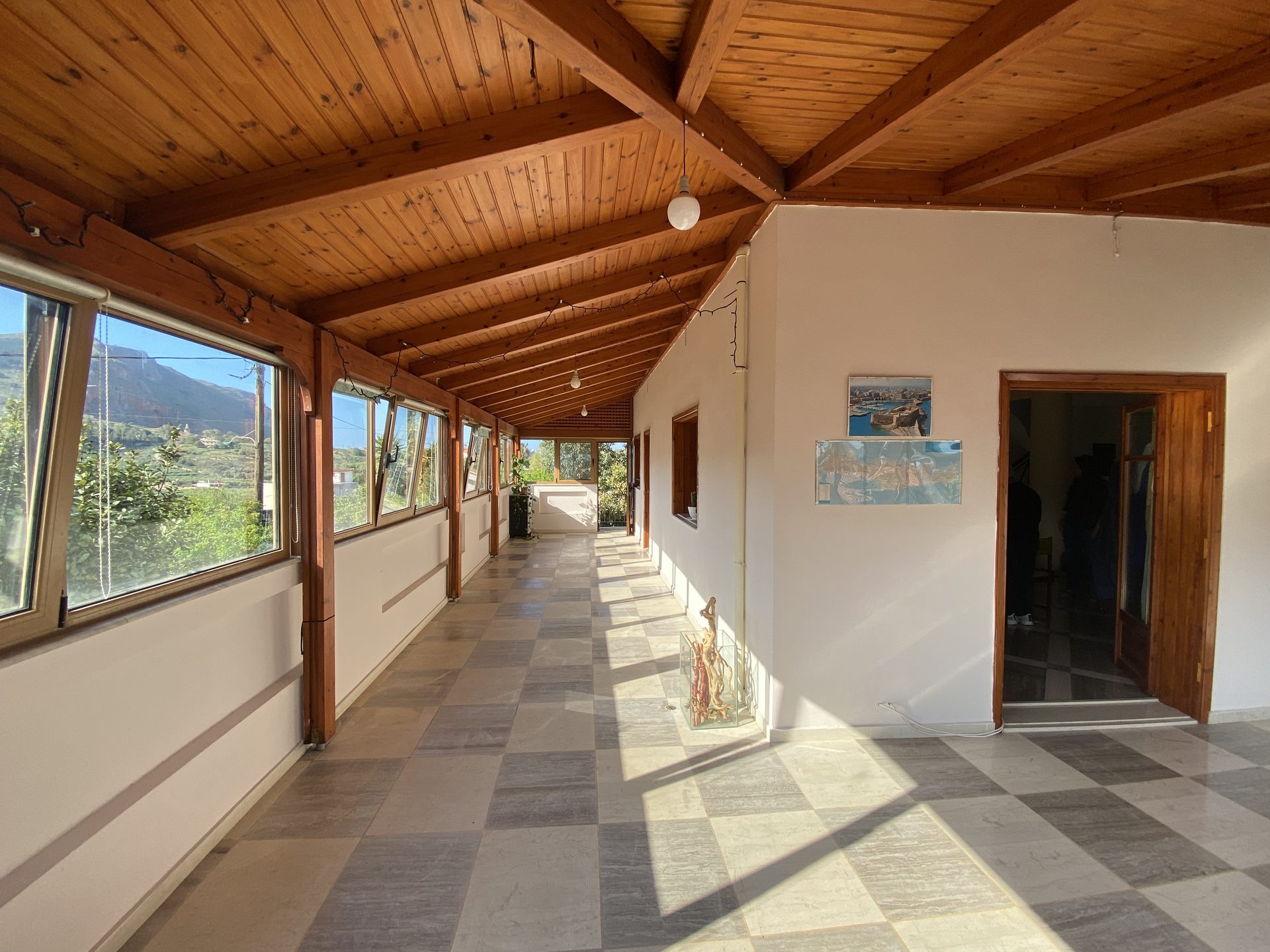 Enclosed sunroom with exposed timber ceiling and Cretan mountain views